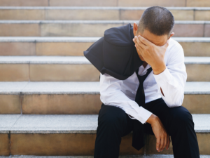 Man feeling low, with hand over eyes